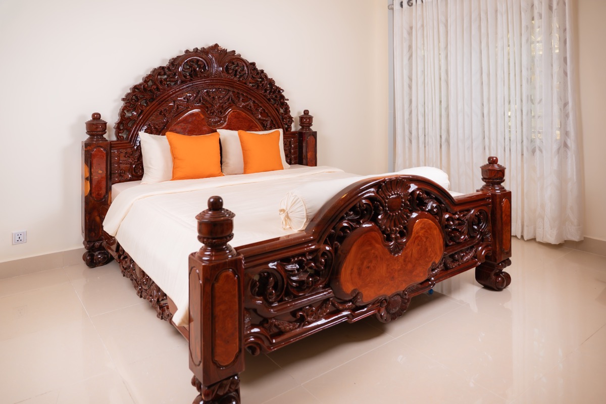 Orange pillows on carved bed